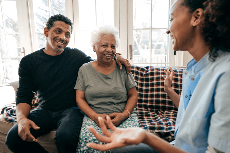 Caregiver sitting with adult son and elderly woman | elderly respite care | Neighborly Home Care
