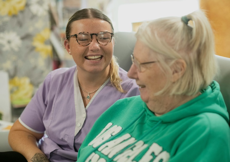 Caregiver laughing with elderly woman in house | elderly respite care | Neighborly Home Care
