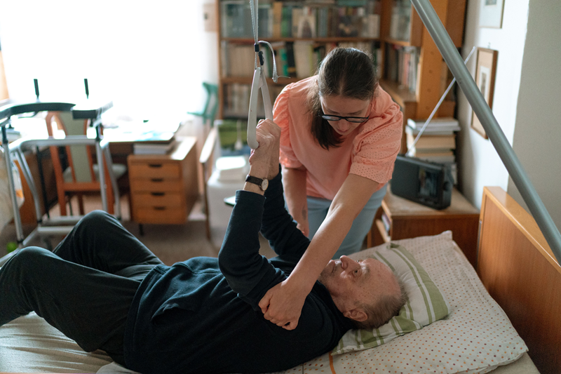 Woman caregiver helping senior out of bed | what are ADLs and IADLs | Neighborly Home Care