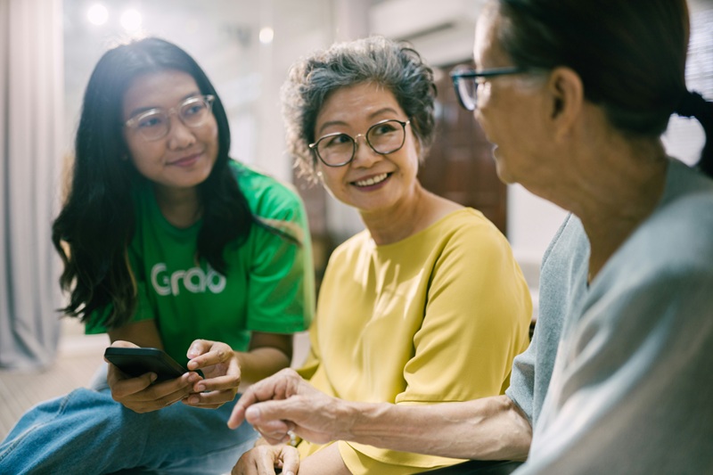 Three women sitting and smiling | signs elderly parent needs care | Neighborly Home Care